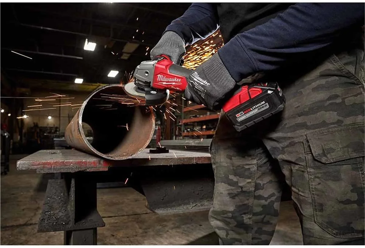 Milwaukee M18 FUEL 2880-20 angle grinder in use cutting a steel pipe with sparks
