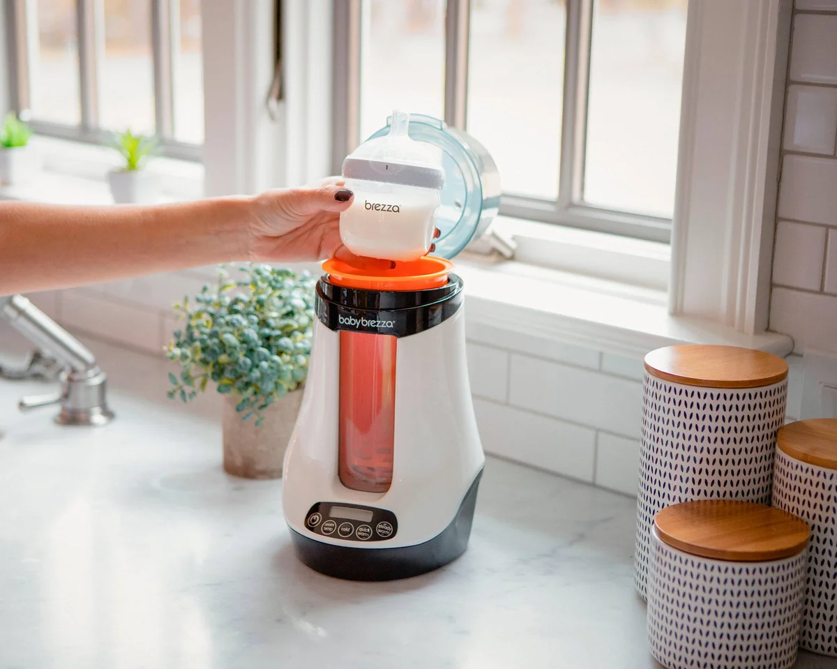 Baby Brezza Safe & Smart Bottle Warmer lifestyle shot with person placing bottle into warmer