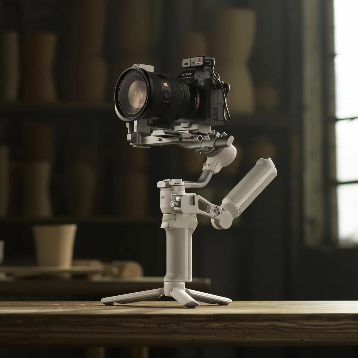DJI RS4 Mini with a Sony mirrorless camera and wide-angle lens on a wooden table