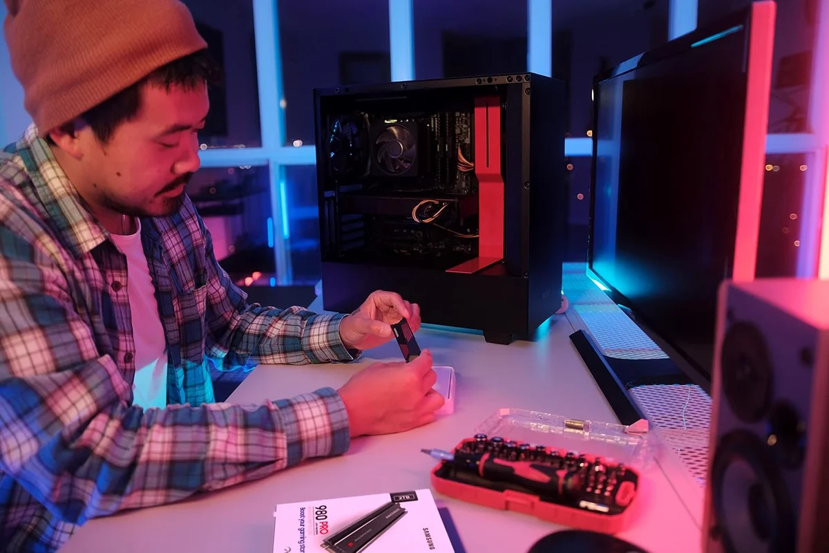 Samsung 990 Pro with Heatsink held during install at an RGB-lit gaming PC build