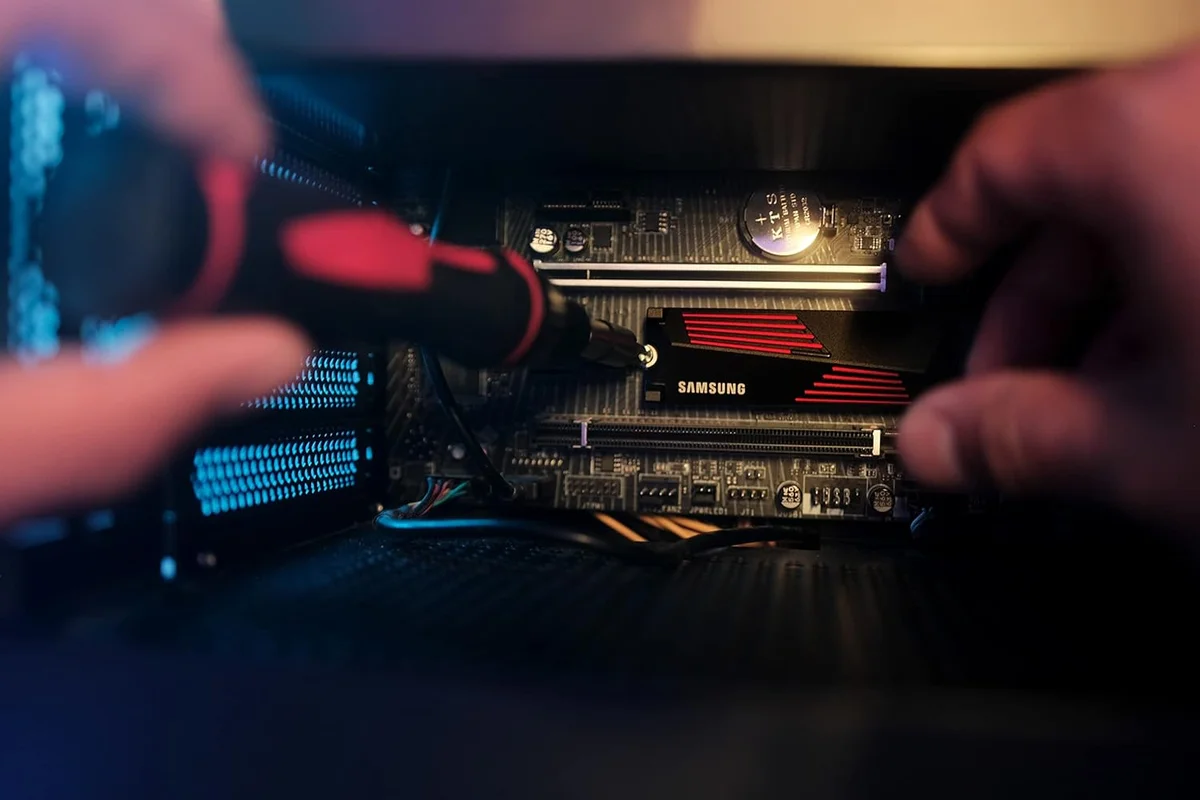 Samsung 990 Pro with Heatsink being screwed into an M.2 slot on a motherboard, close-up