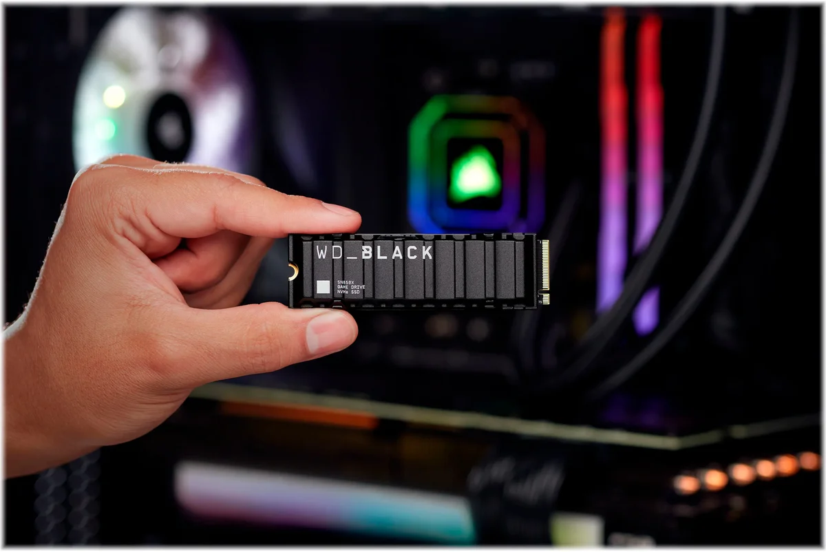 WD_Black SN850X with Heatsink held in hand in front of an RGB gaming PC build