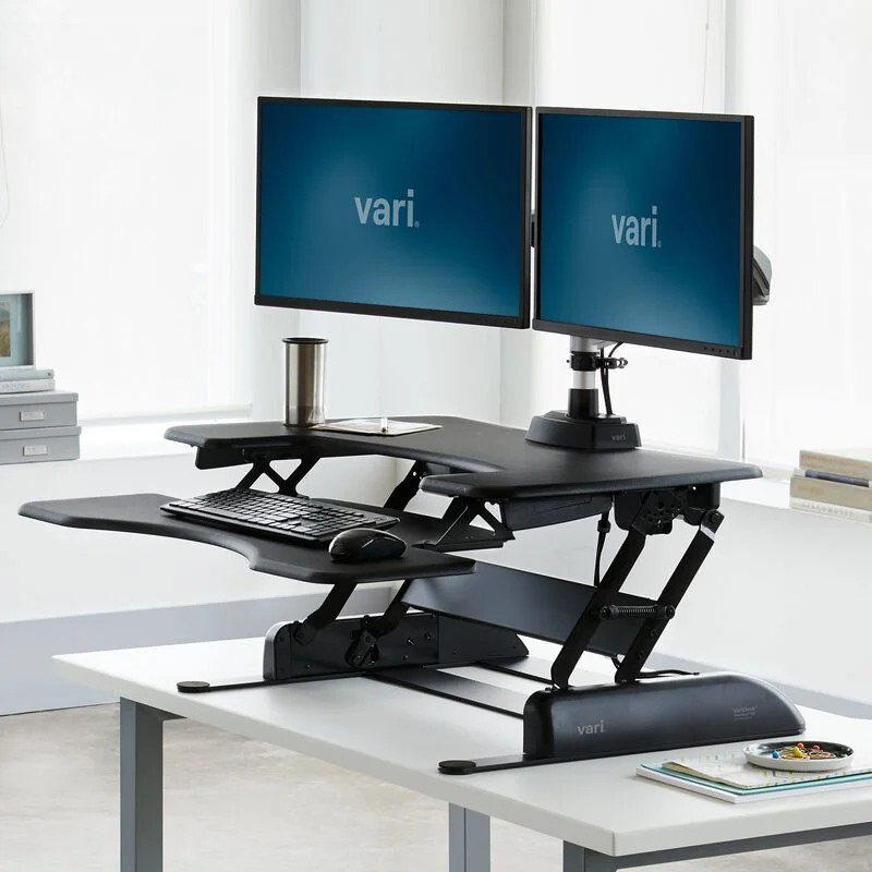 VariDesk Pro Plus 36 raised to standing height with dual monitors, keyboard tray extended in studio office setting