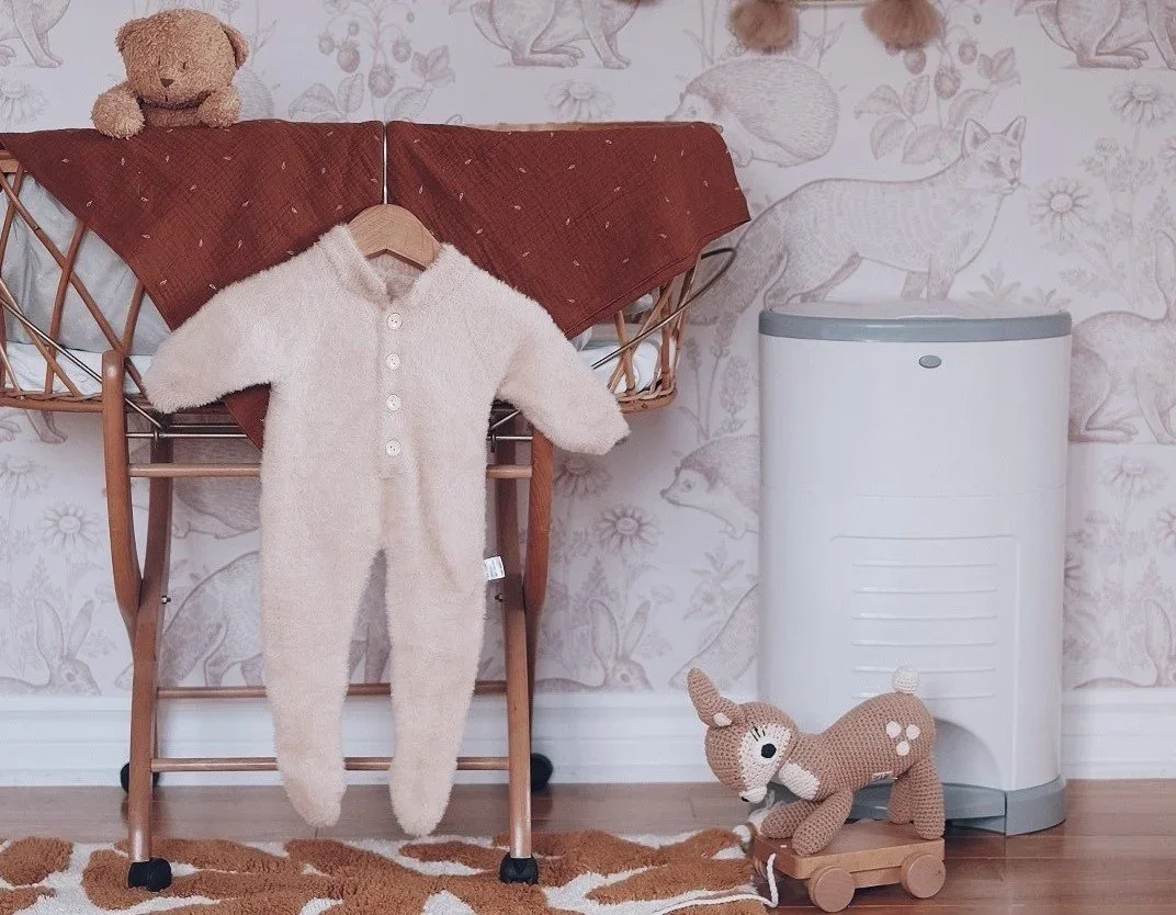 Dekor EKO Diaper Pail styled in a woodland-themed nursery next to a bassinet