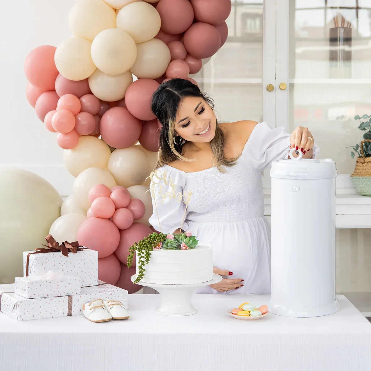 Ubbi Steel Diaper Pail in nursery at a baby shower with a smiling mother-to-be