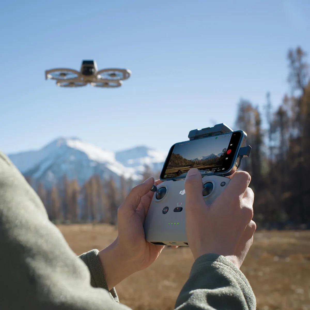 DJI Flip flying outdoors while pilot controls it with DJI RC-N3 controller and smartphone