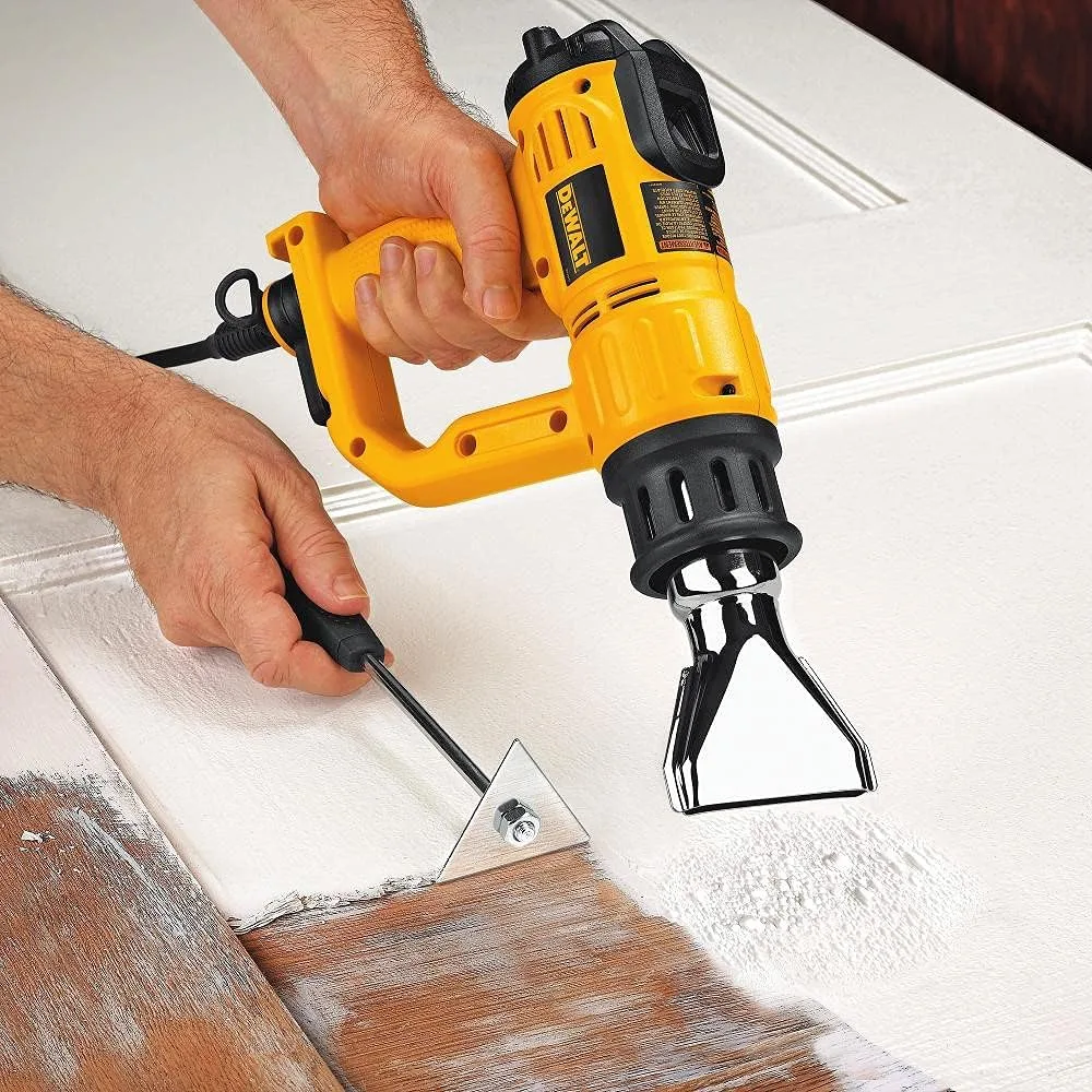 DeWalt D26960K heat gun in use stripping paint from a door with the wide fishtail nozzle attached