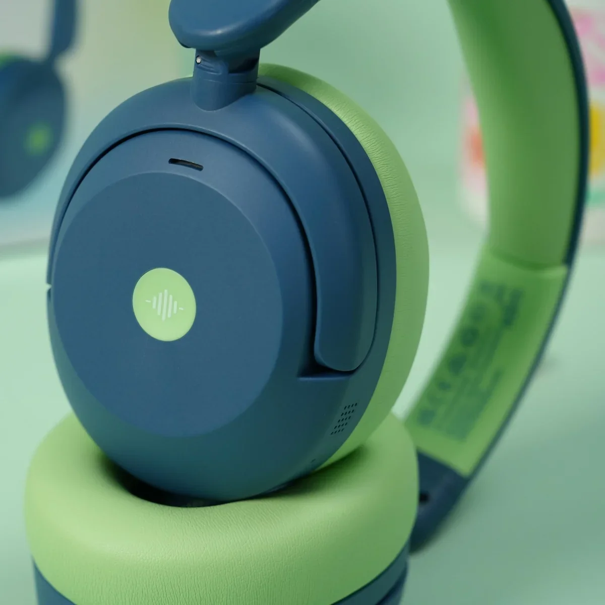 Close-up of the iClever BTH20 earcup control dial and cushioned green ear pad