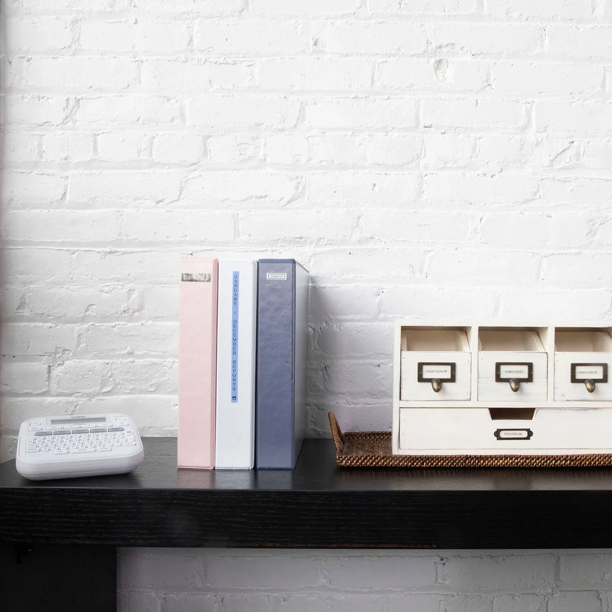 Brother P-Touch PTD220 beside labeled binders and organizer drawers