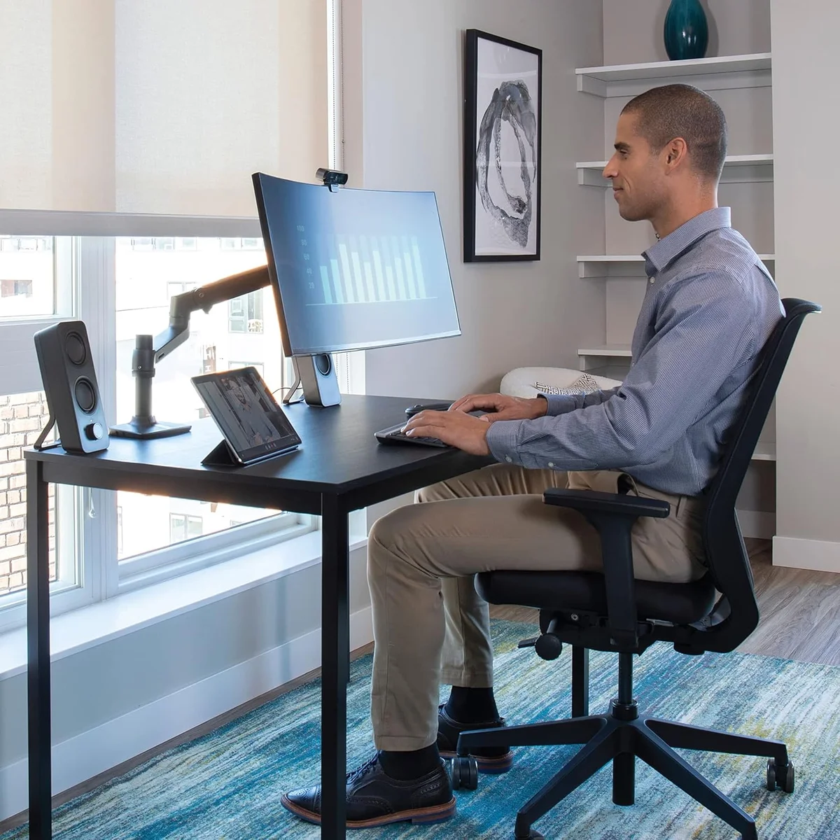 Ergotron LX Desk Mount Monitor Arm in use with a person working at a sit-stand desk