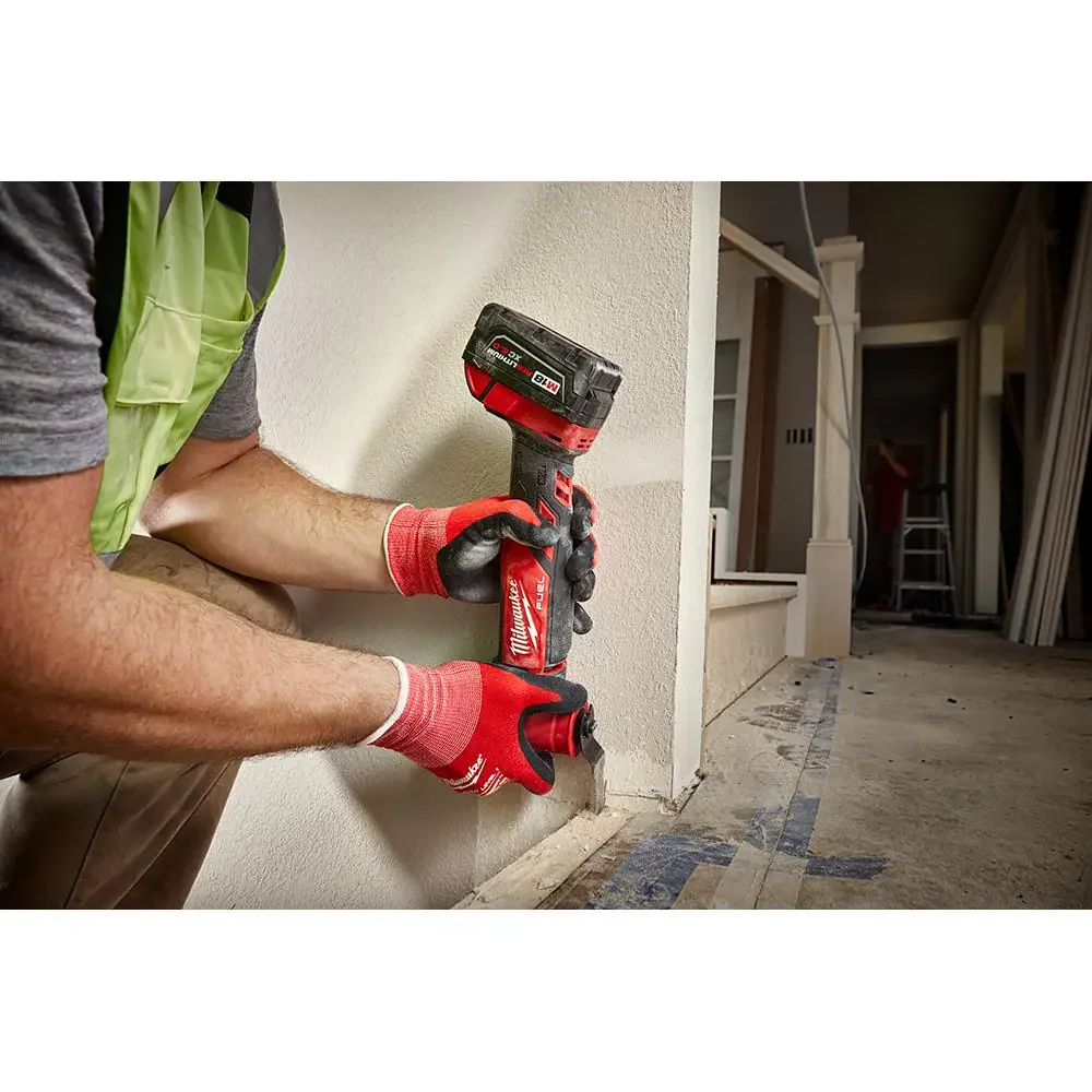 Milwaukee M18 FUEL 2836-20 in use, a worker cutting into a wall base with the multi-tool