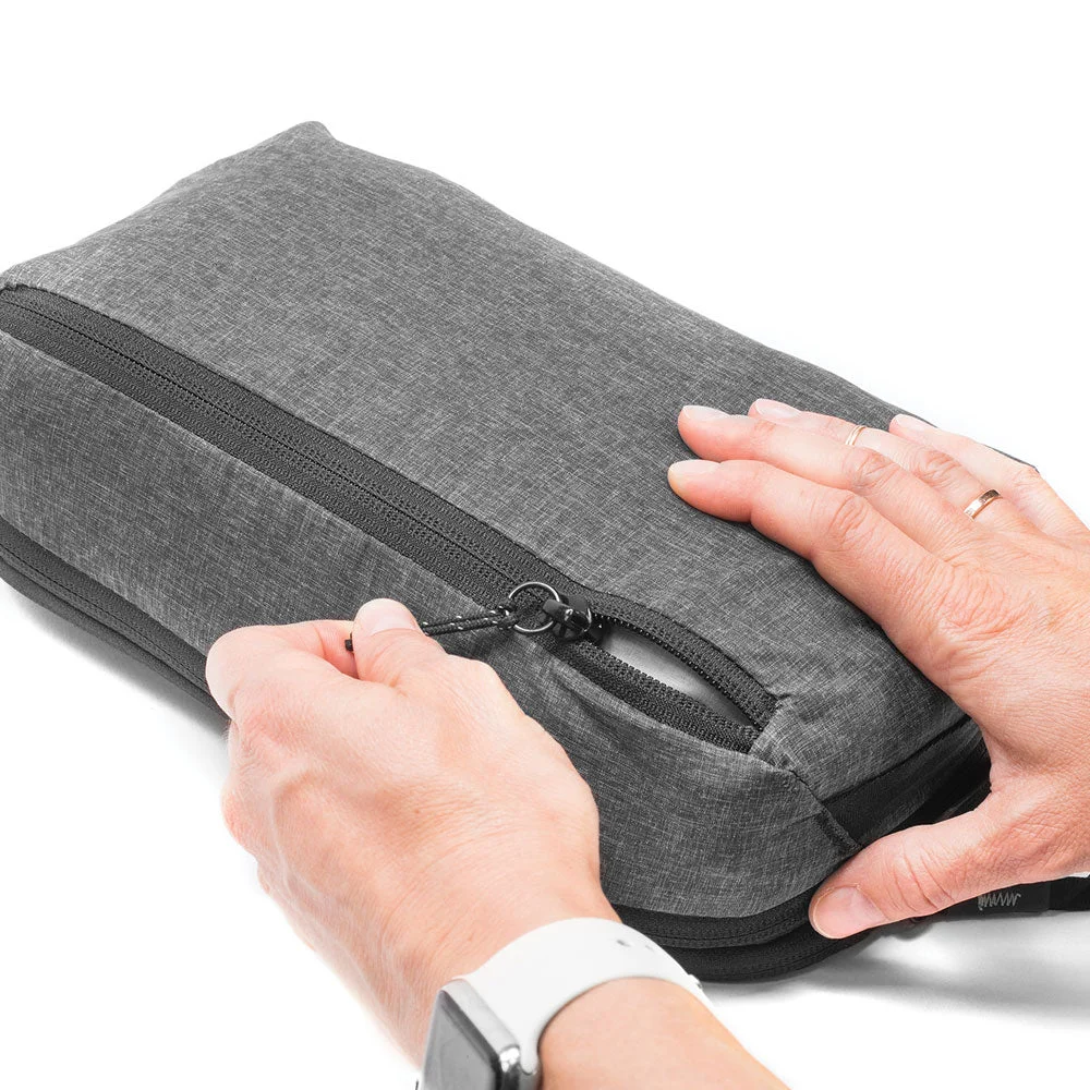 Hands opening the Peak Design Packing Cube zipper, demonstrating the one-handed tear-away opening