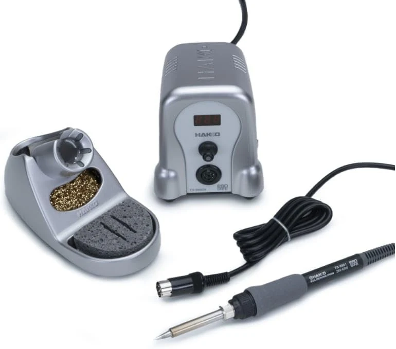Hakko FX-888D soldering iron handpiece resting in the iron holder with brass cleaning coil