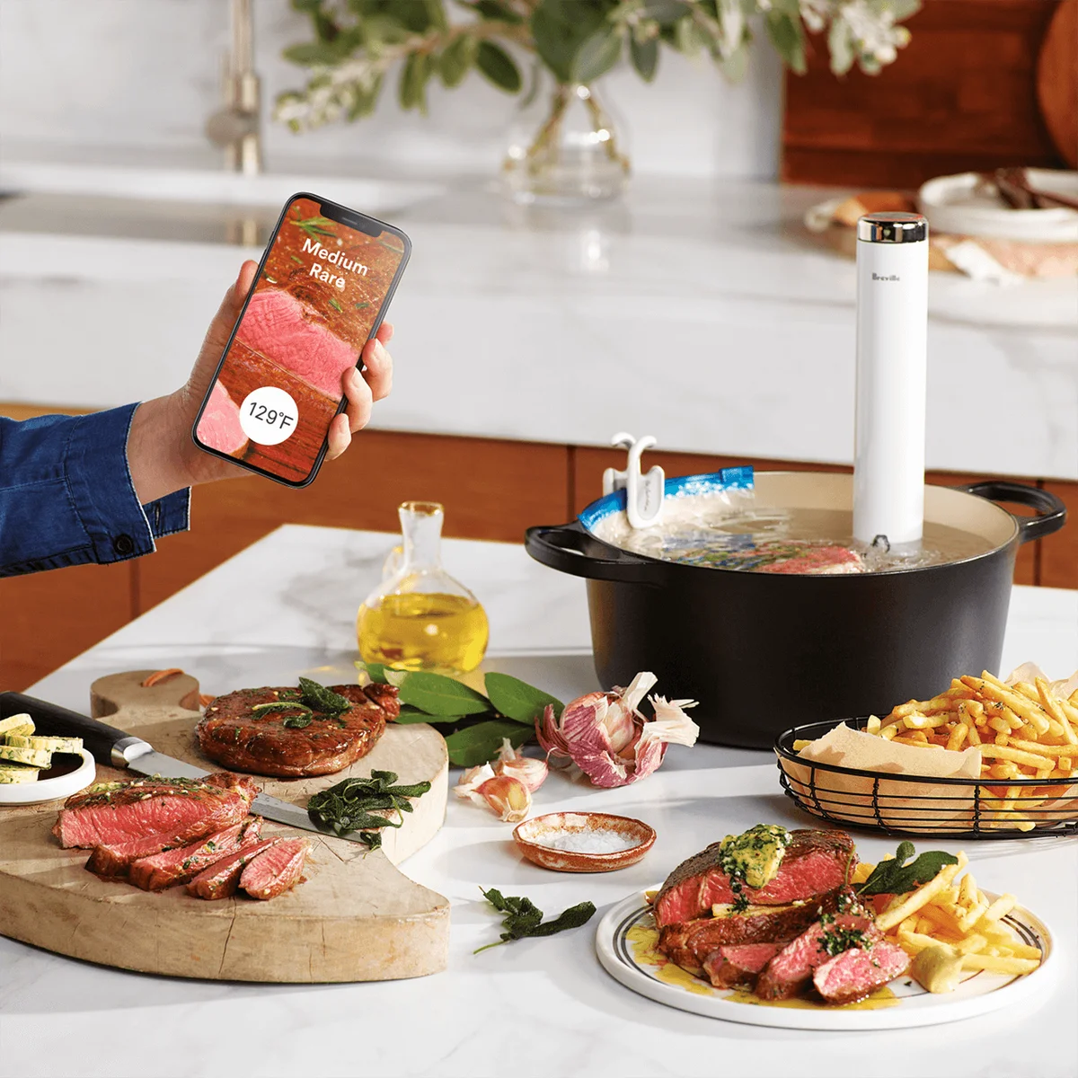 Breville Joule Turbo circulating in a Dutch oven cooking steak with the Breville+ app open on a phone