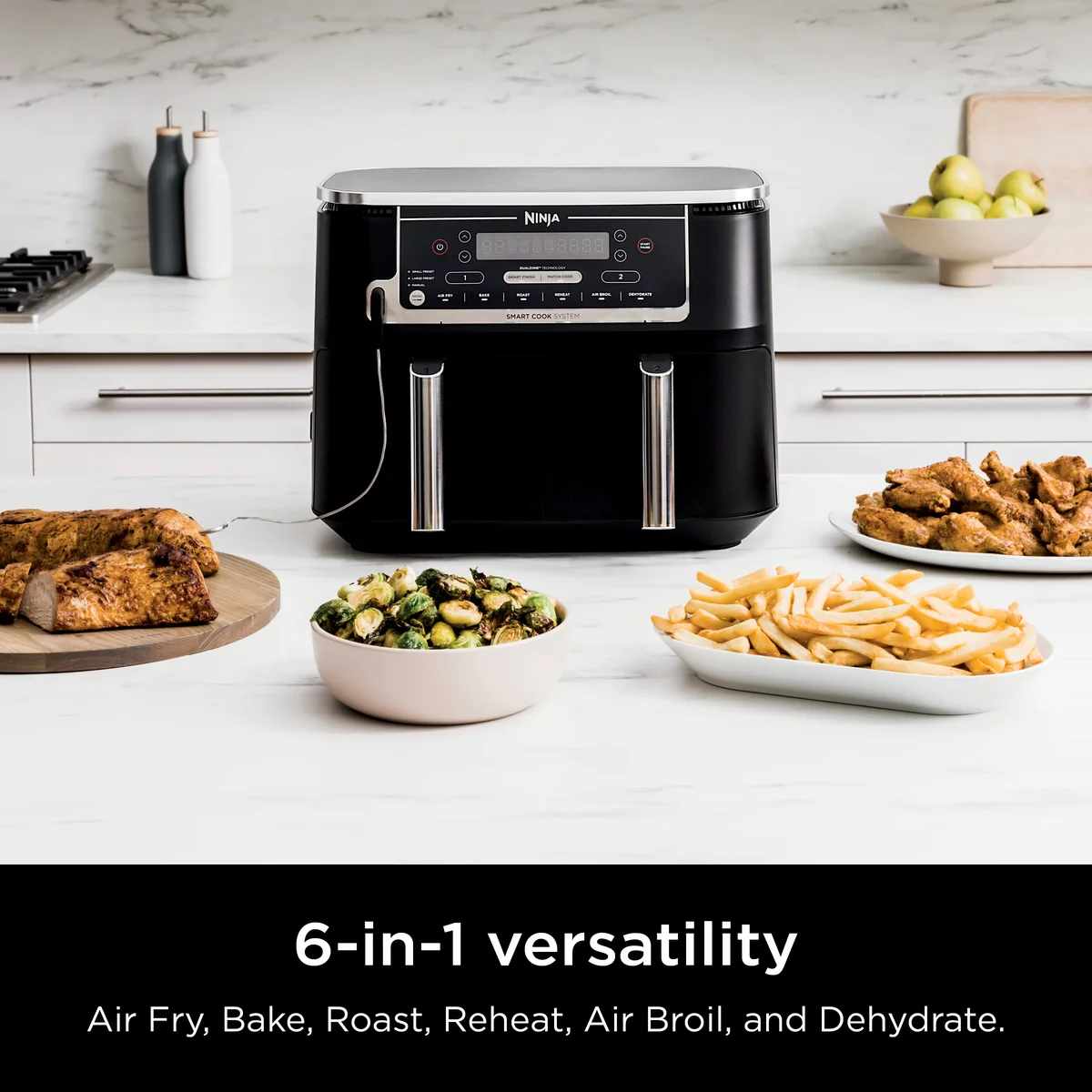 Ninja DZ550 in a modern kitchen surrounded by air-fried chicken, brussels sprouts, fries, and roasted pork