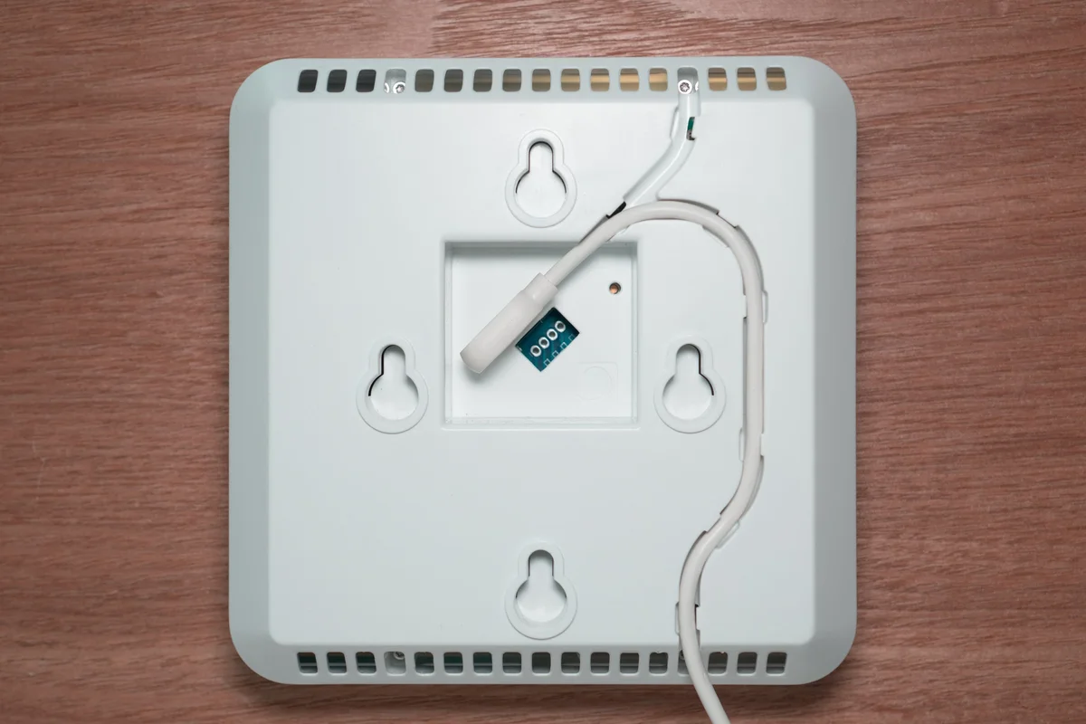 AirGradient One monitor rear view showing wall-mount screw holes, USB-C connector and cable routing