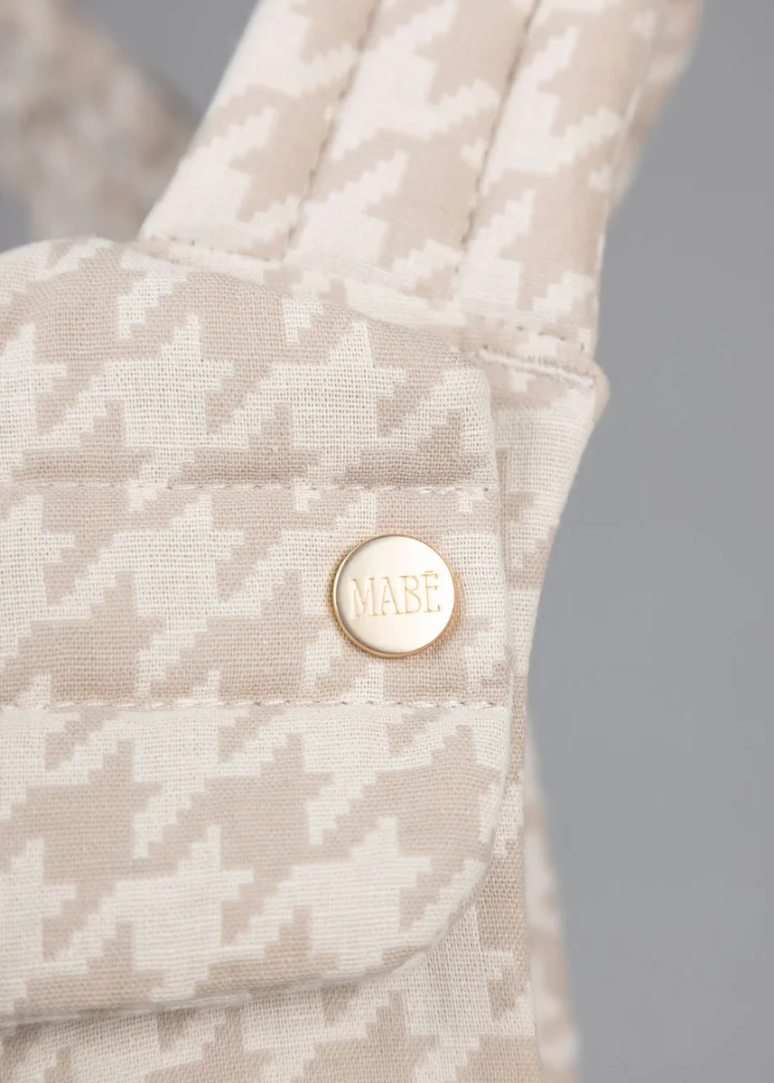 Close-up of the Mabe Monarch gold snap button with embossed Mabe branding on the houndstooth fabric