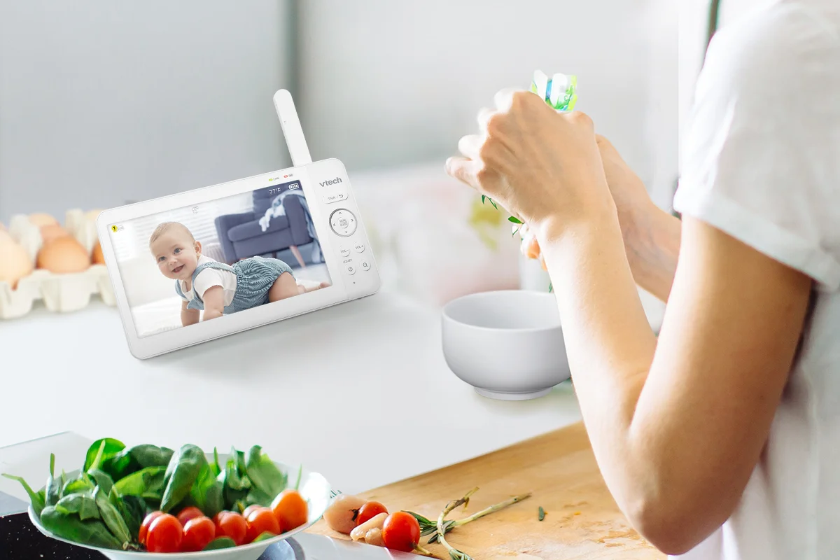 VTech Advanced HQ Max parent unit in use on a kitchen counter while parent cooks, showing live baby video feed on the 7-inch screen