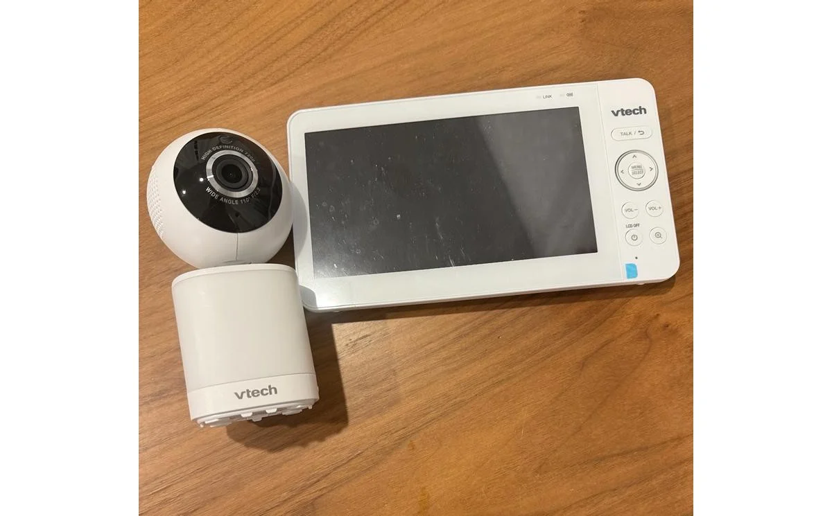 VTech Advanced HQ Max parent unit and camera unit laid side by side on a wood table, showing the front panel and controls