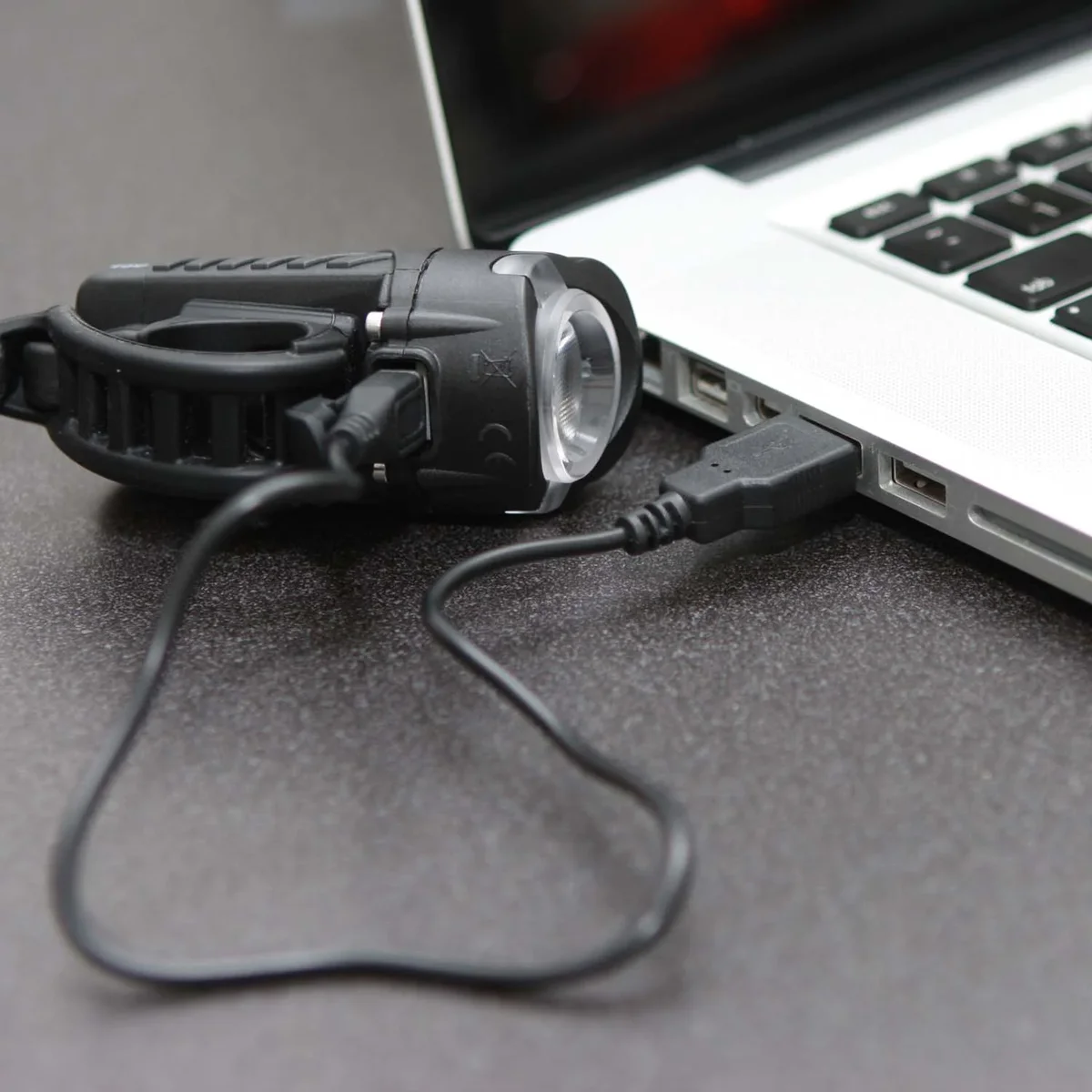 NiteRider Swift 500 connected via USB cable to a laptop for charging