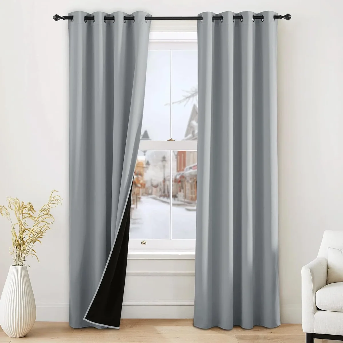 NICETOWN 100% blackout grommet-top curtains in grey hung over a bedroom window, with one panel flipped to reveal the black thermal-insulated lining
