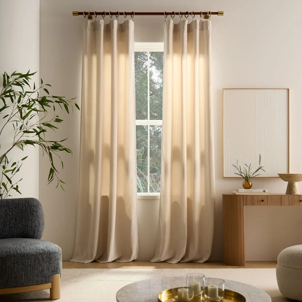 West Elm Worn Velvet Blackout Curtain panels styled in a neutral living room on a wood rod with brass rings
