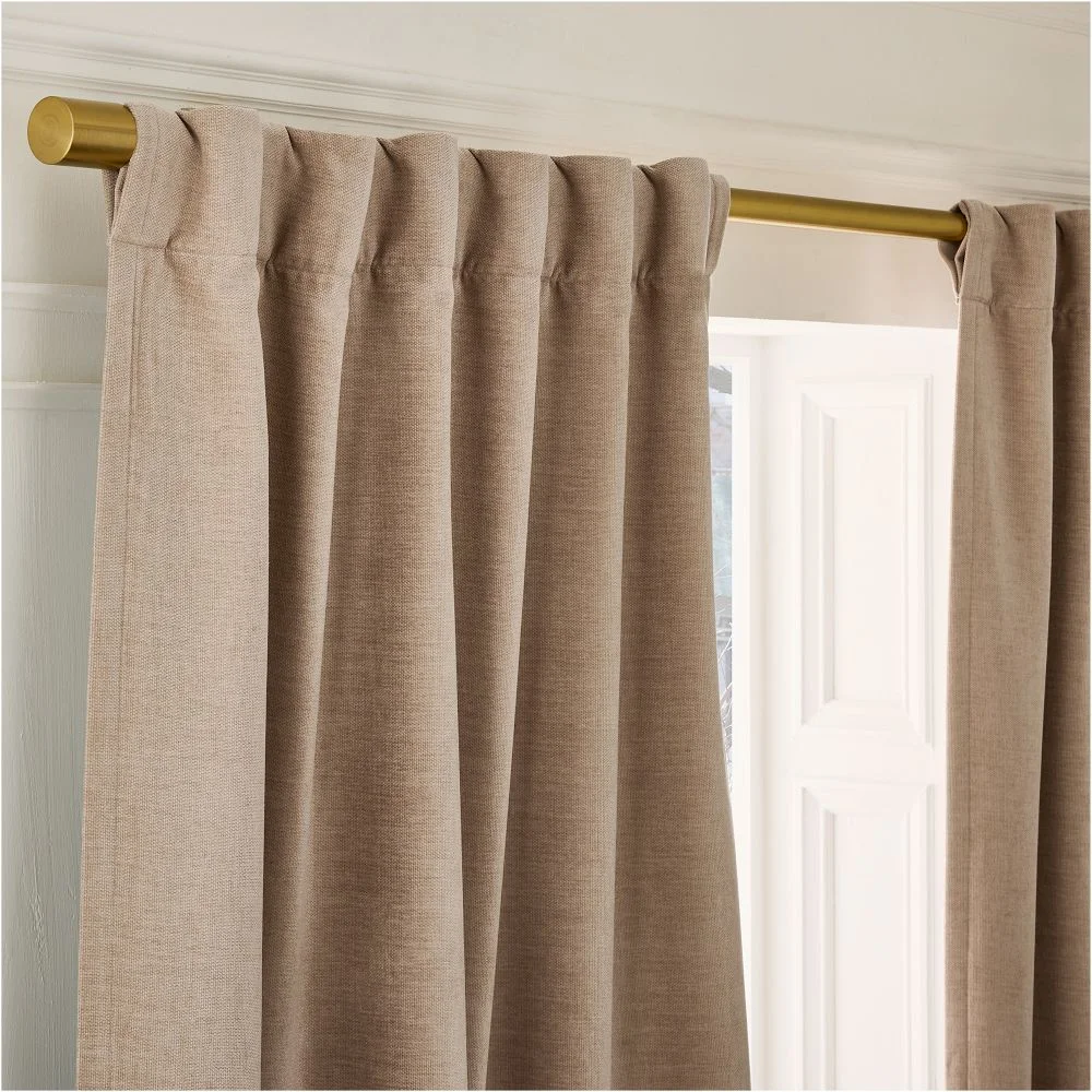 West Elm Worn Velvet Blackout Curtain in taupe showing the header pleats hung on a brass rod