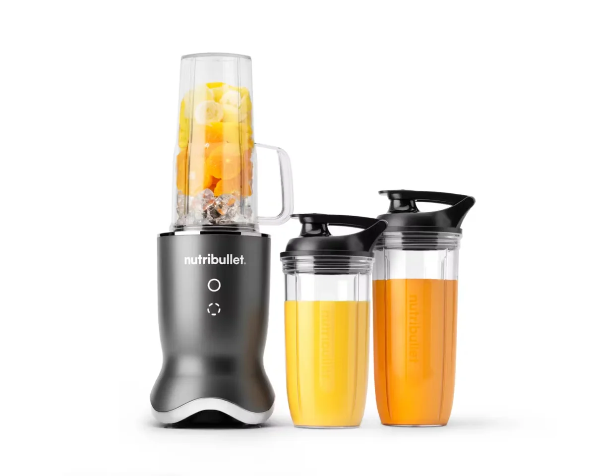 Nutribullet Ultra personal blender in dark grey with handled blending cup filled with fruit, alongside two to-go cups with orange juice and travel lids