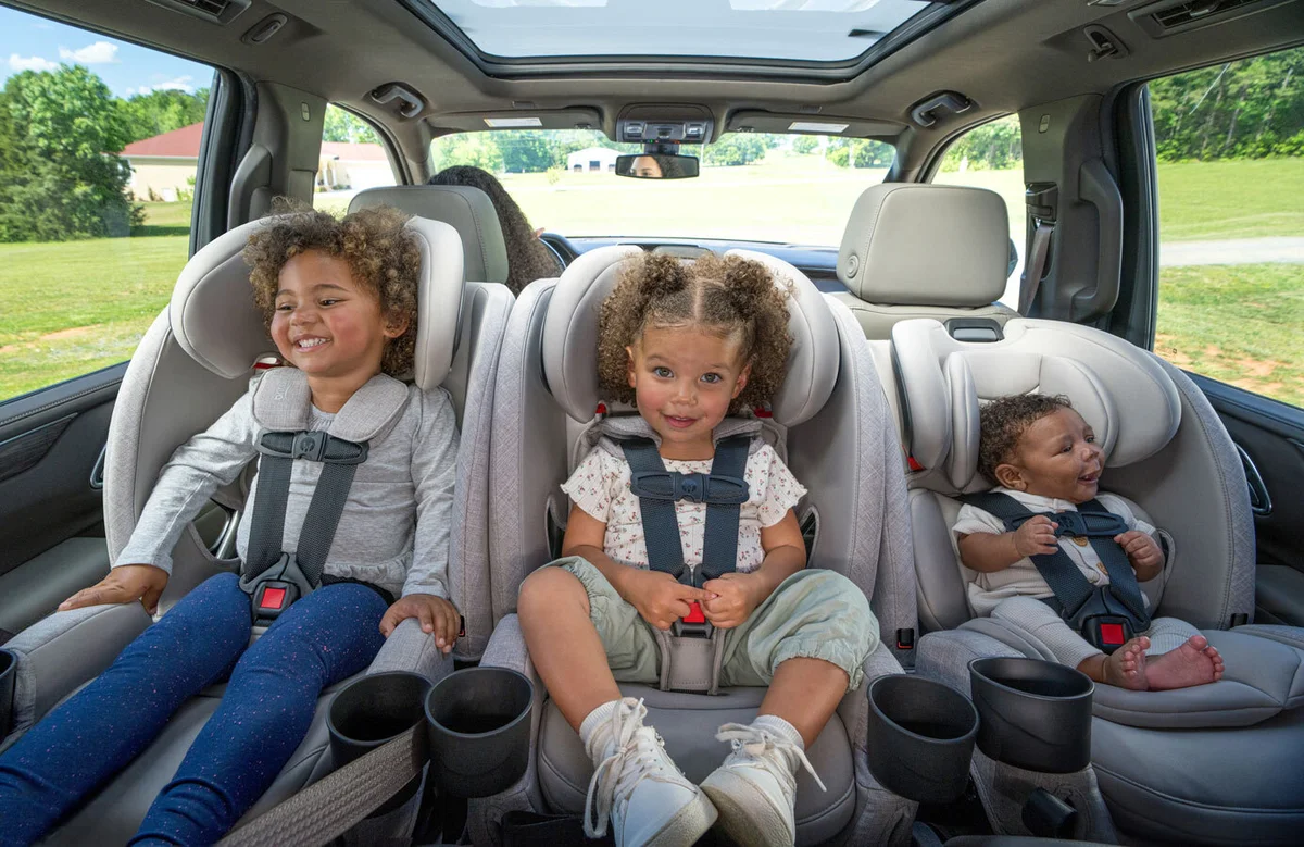 Three children seated three-across in a minivan back row in Britax One4Life Slim seats