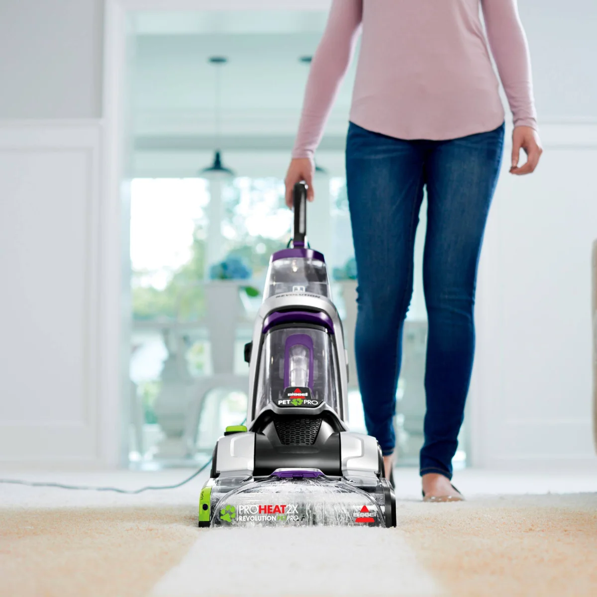 Bissell ProHeat 2X Revolution Pet Pro Plus in use, person pushing the carpet cleaner across a light-colored carpet