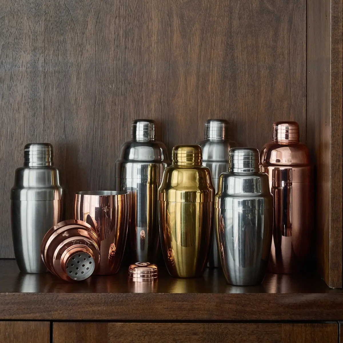 Usagi cobbler shakers in several finishes on a bar shelf, one opened to show the strainer holes