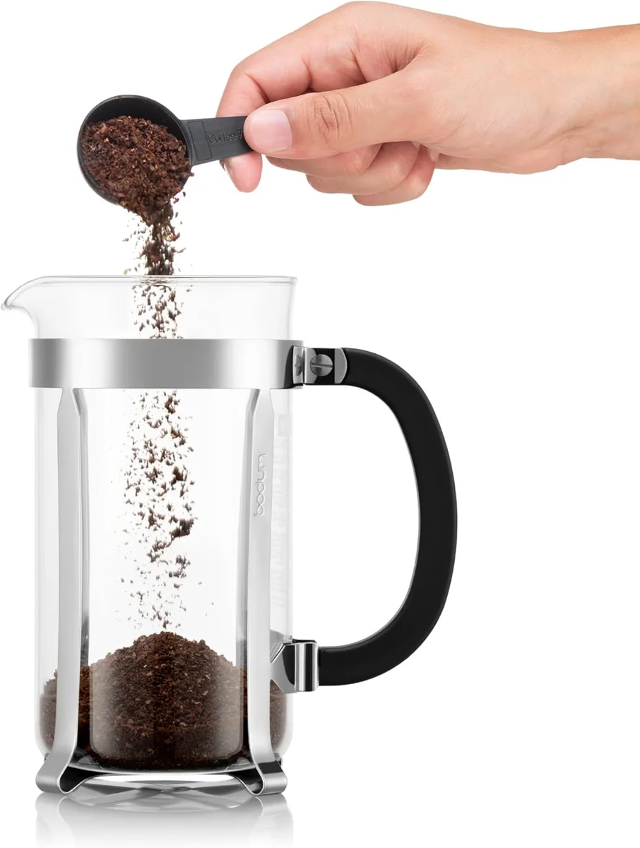 Hand scooping coffee grounds into Bodum Chambord French Press
