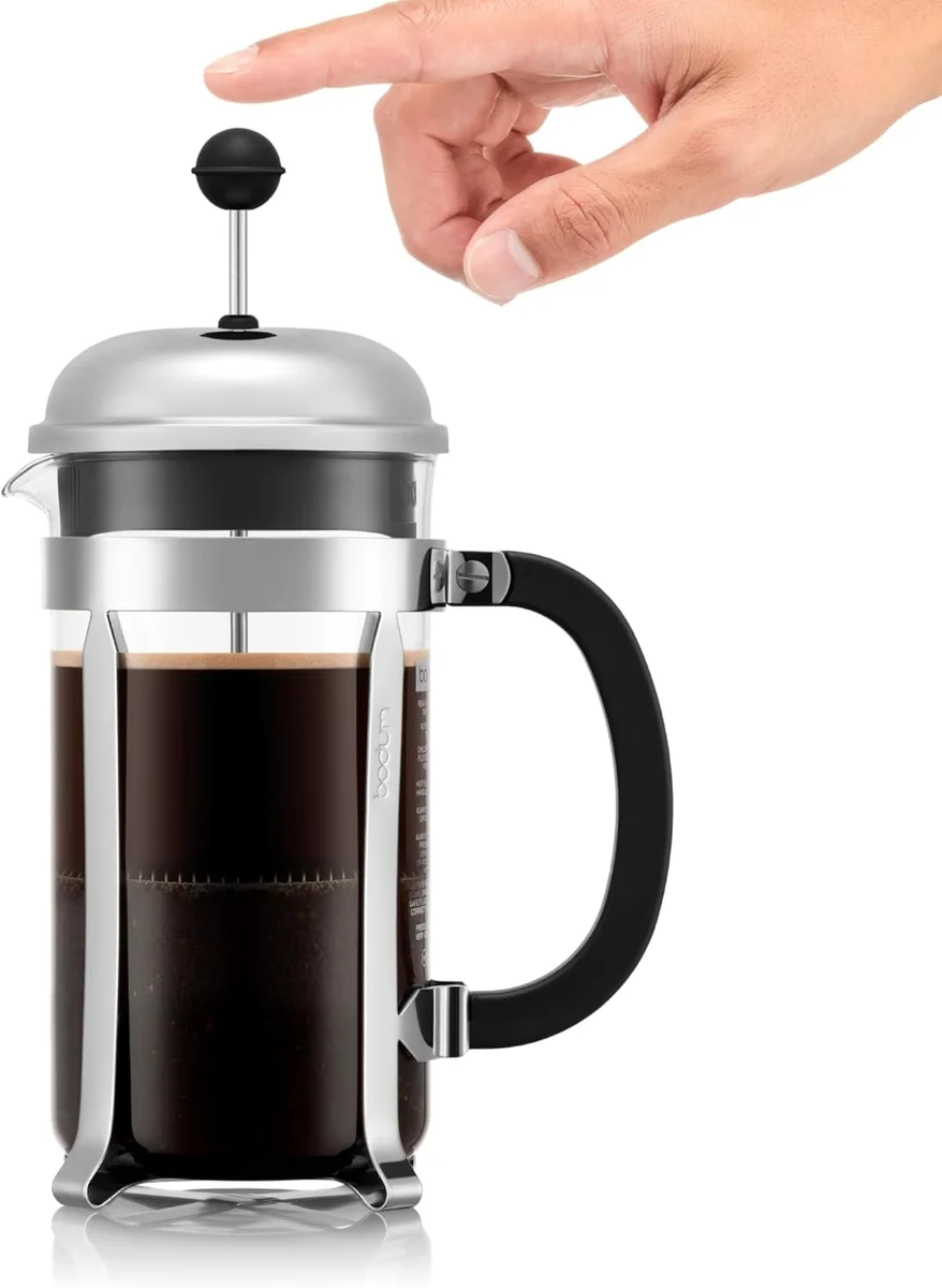 Hand pressing down the Bodum Chambord plunger through brewed coffee