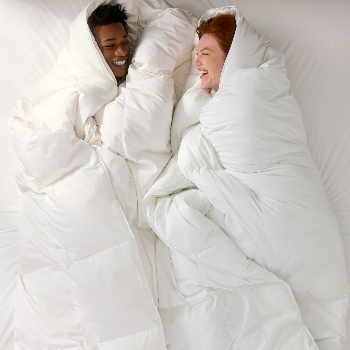 Two people wrapped up under the Brooklinen Down Comforter