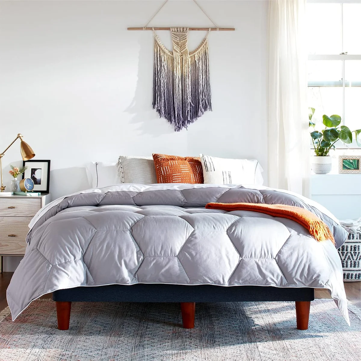 Layla Down Alternative Comforter in grey on a made bed with an orange throw draped across