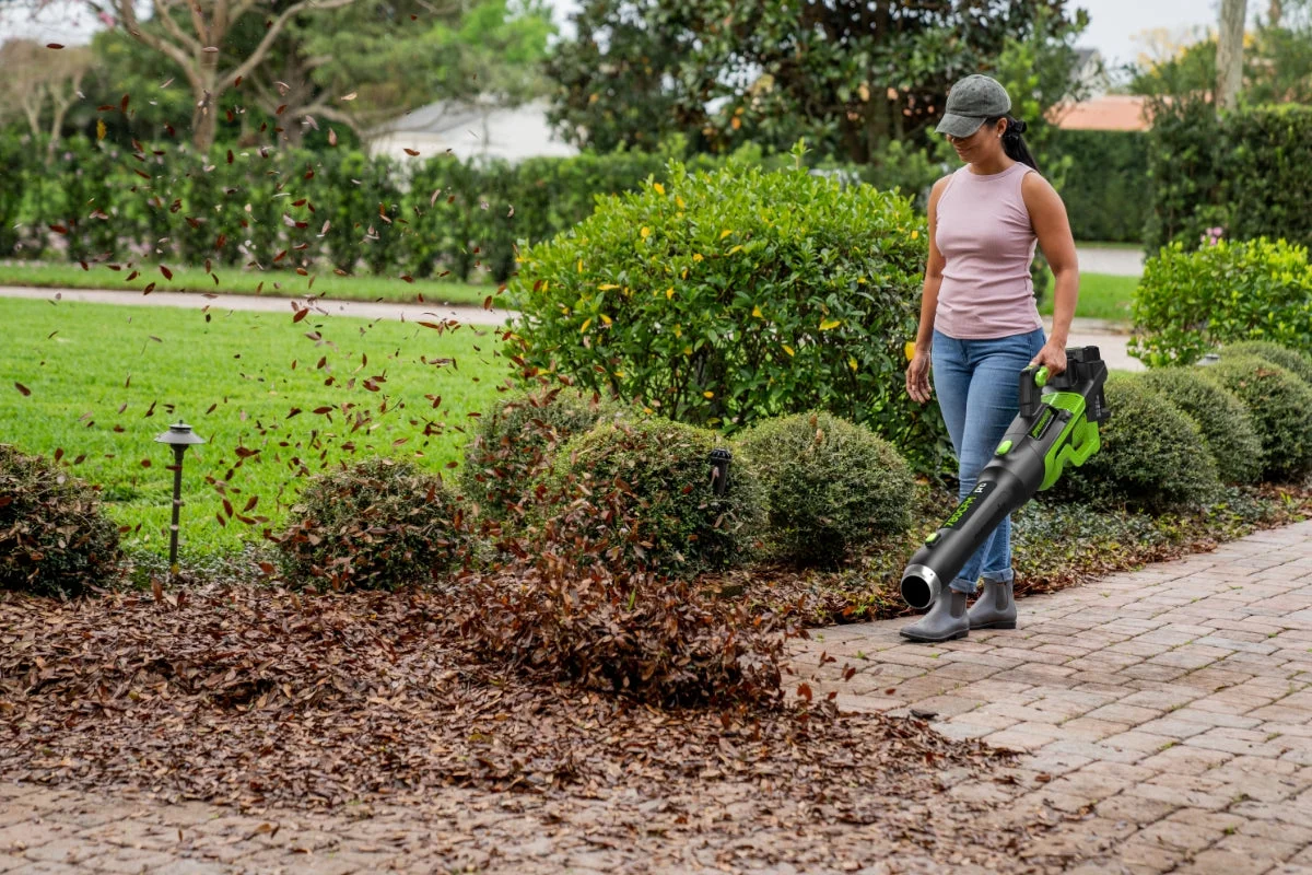 Greenworks Pro 780 CFM blower in use clearing leaves from a garden bed