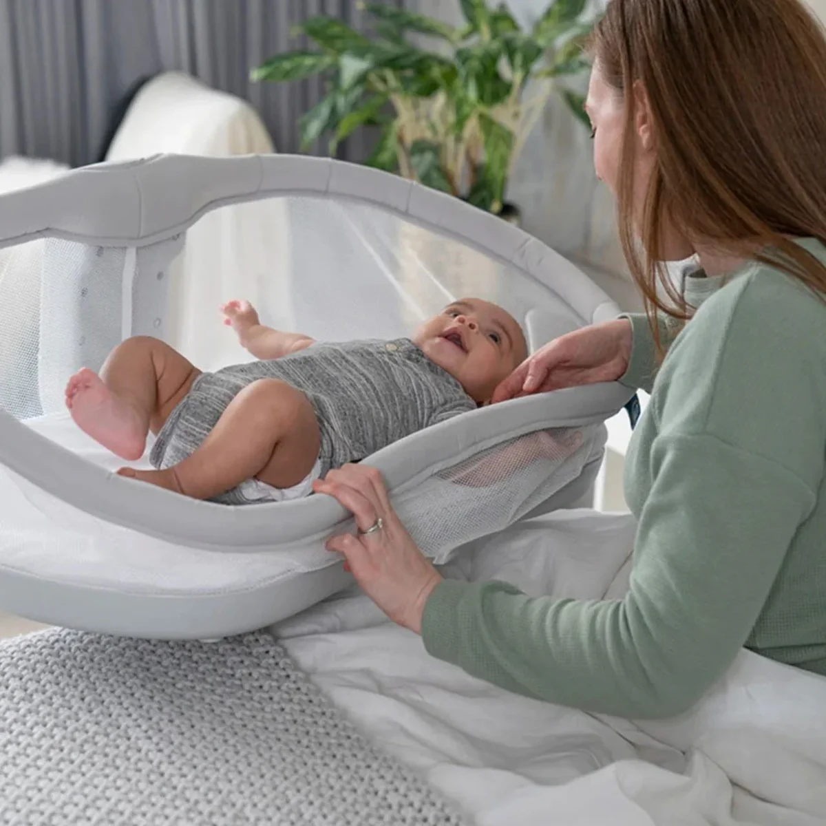Mother placing baby into the removable Halo BassiNest lounger nest