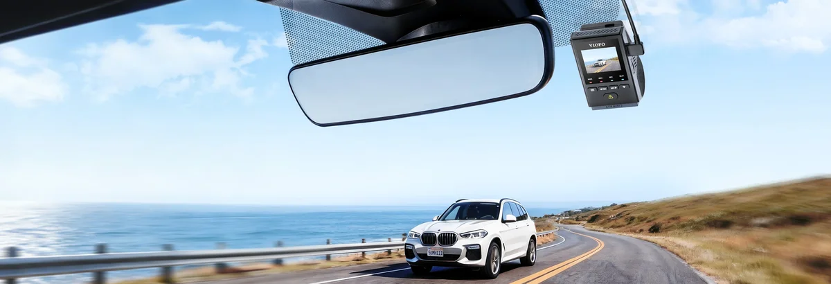 Viofo A119 Mini 2 mounted behind rearview mirror in a car on a coastal road