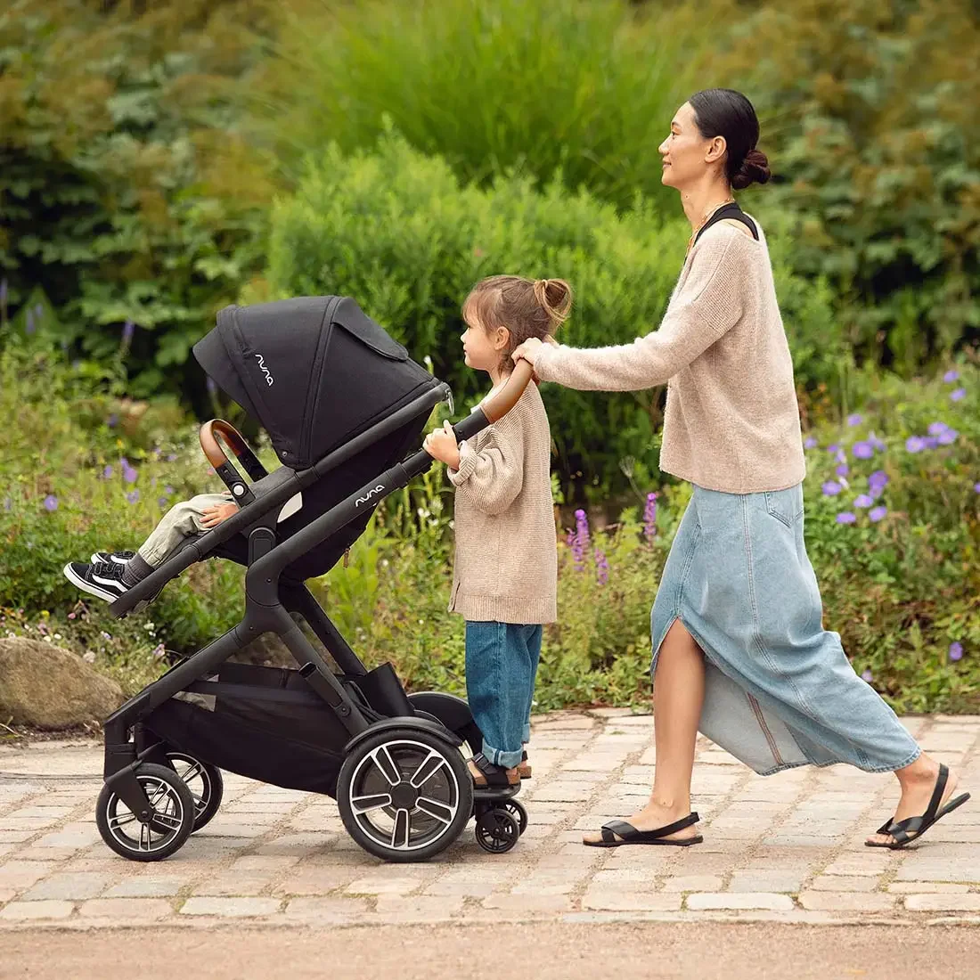 Nuna DEMI Next in use outdoors — mother and toddler walking through a garden park