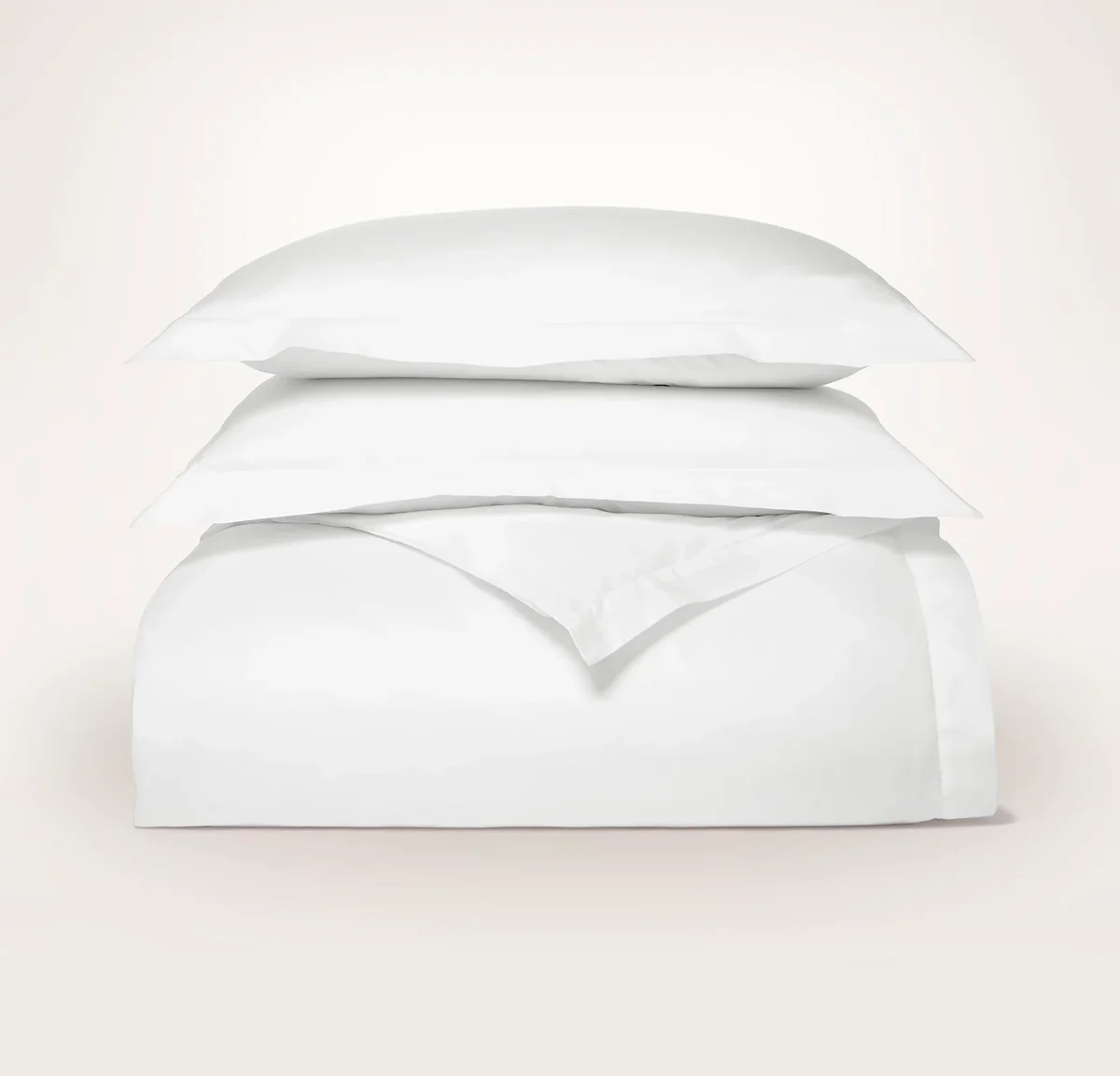 Boll & Branch Signature Hemmed Duvet Set in White, folded and styled with matching shams on a soft neutral backdrop