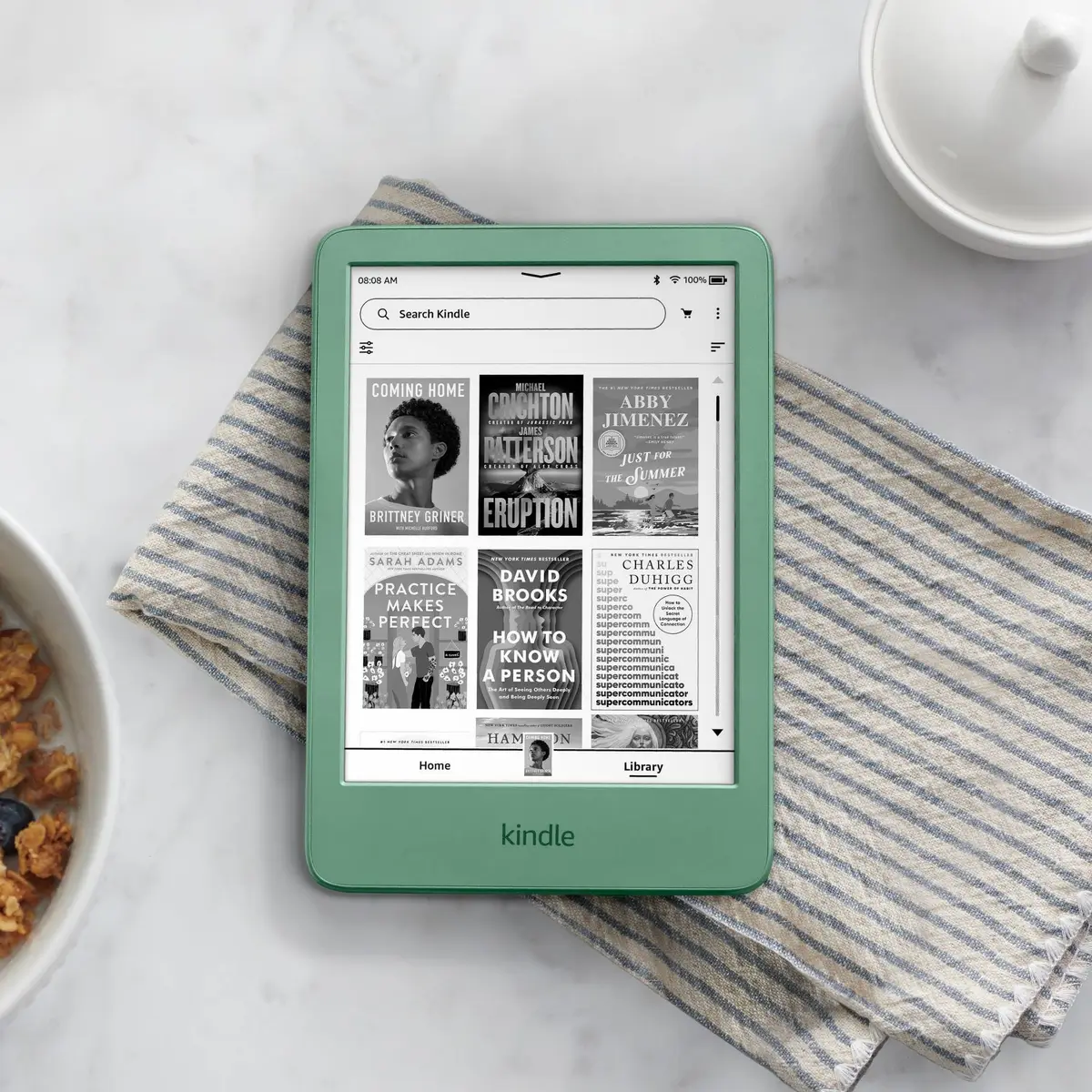 Amazon Kindle (2024) in Matcha on a kitchen counter showing the library home screen