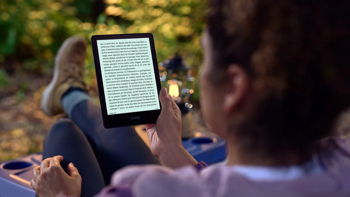 Person reading on Kindle Paperwhite outdoors in warm ambient light