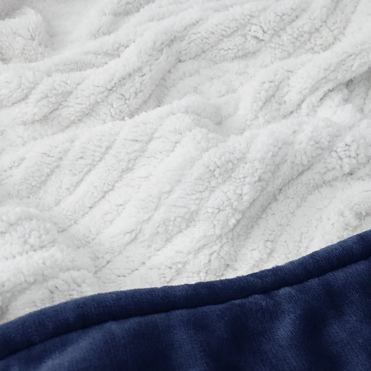 Close-up of the Bedsure GentleSoft heated blanket's ribbed white sherpa reverse and navy flannel edge