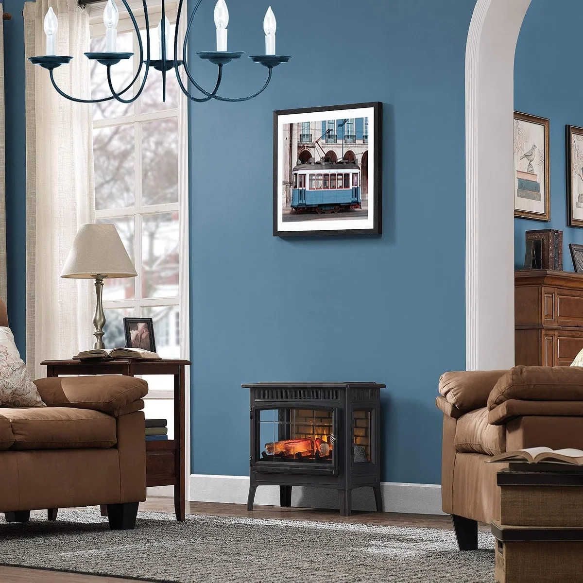 Duraflame 3D Infrared black stove in a living room setting between two armchairs, flames lit
