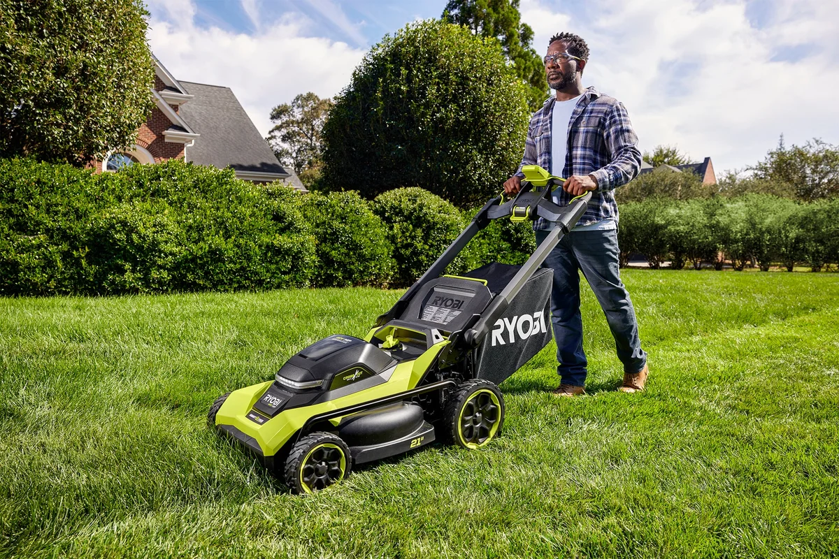 Ryobi 40V HP CrossCut mower side view with operator pushing across lawn