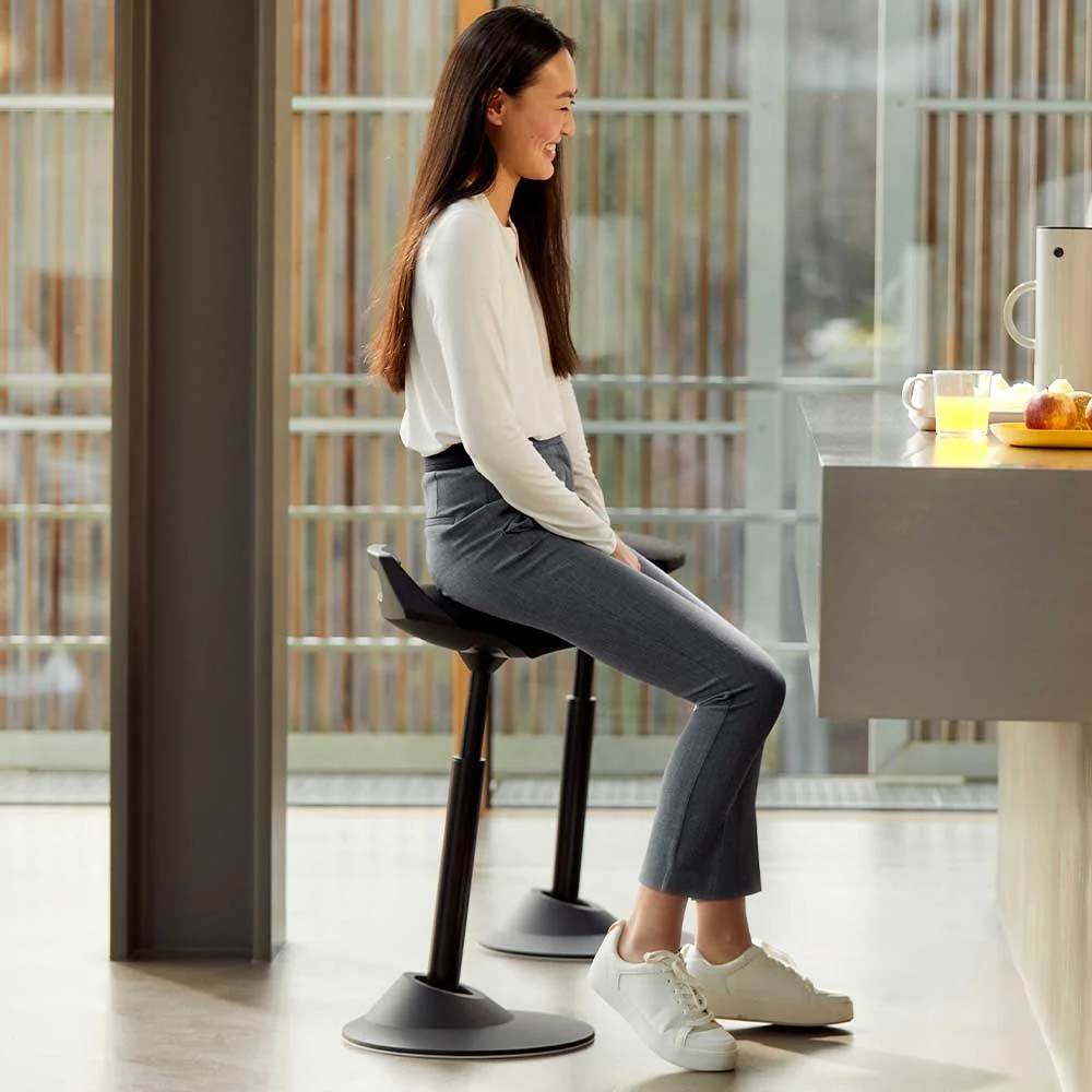 Woman sitting on black Aeris Muvman stool at kitchen bar counter