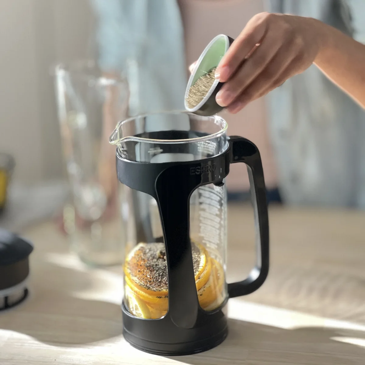Espro P3 glass carafe with sliced orange and tea being added to the double filter