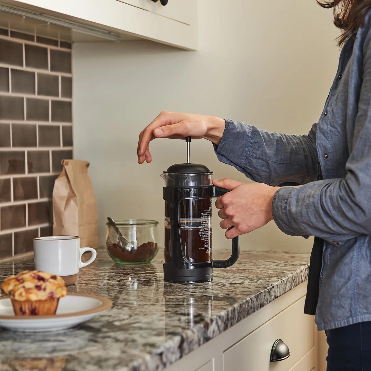Espro P3 glass French press being pressed by hand on a kitchen counter
