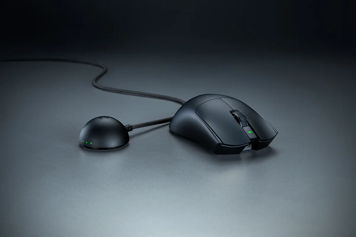 Razer Viper V4 Pro in black on a desk beside its dome-shaped wireless dongle dock with a braided cable