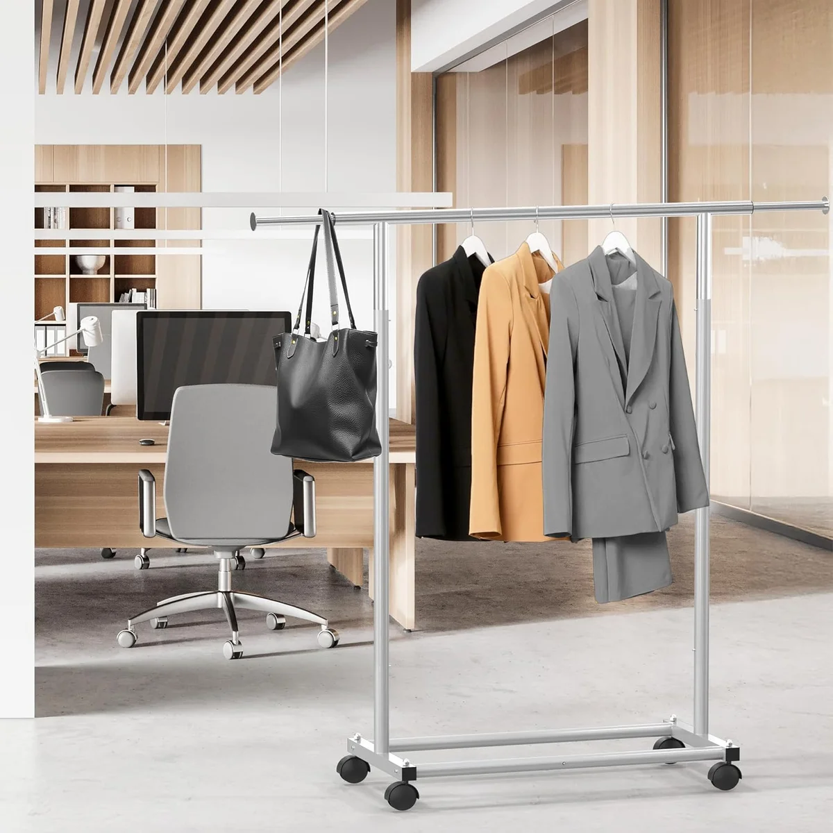 Simple Houseware Standard Rod Garment Rack in an office holding blazers and a tote bag on its extended top rod
